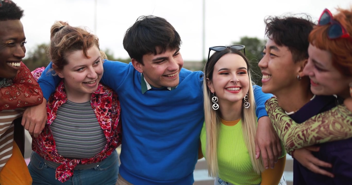 Felice gruppo eterogeneo di giovani amici che si abbracciano all'aperto