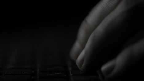 hands typing on a laptop keyboard in low light