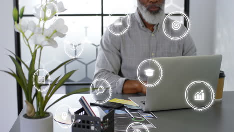 Animation-of-multiple-icons-over-african-american-man-working-on-laptop-in-office