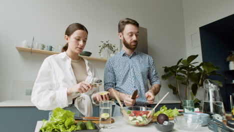 alegre pareja joven preparando ensalada juntos en una cocina moderna 2