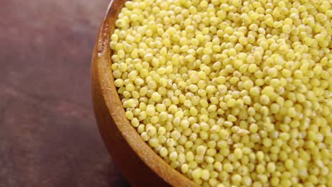 full rustic wooden bowl with dry millet on a rustic wooden table. macro