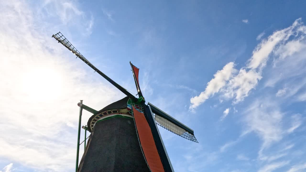 Historic windmill blades turning in sunlight, low angle, vibrant sky, smooth camera, daytime