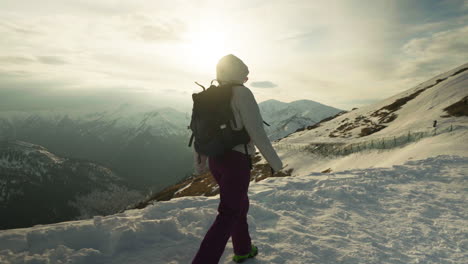 hiker walking confidently on a snowy slope at sunset. slow motion