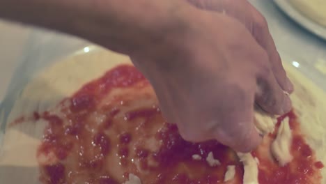 Italian-Master-Chef-Putting-fresh-Mozzarella-cheese-and-Basil-leaves-on-a-Margherita-Pizza-in-Naples-Restaurant