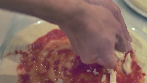 chef maestro italiano poniendo queso mozzarella fresco y hojas de albahaca en una pizza margherita en el restaurante de nápoles