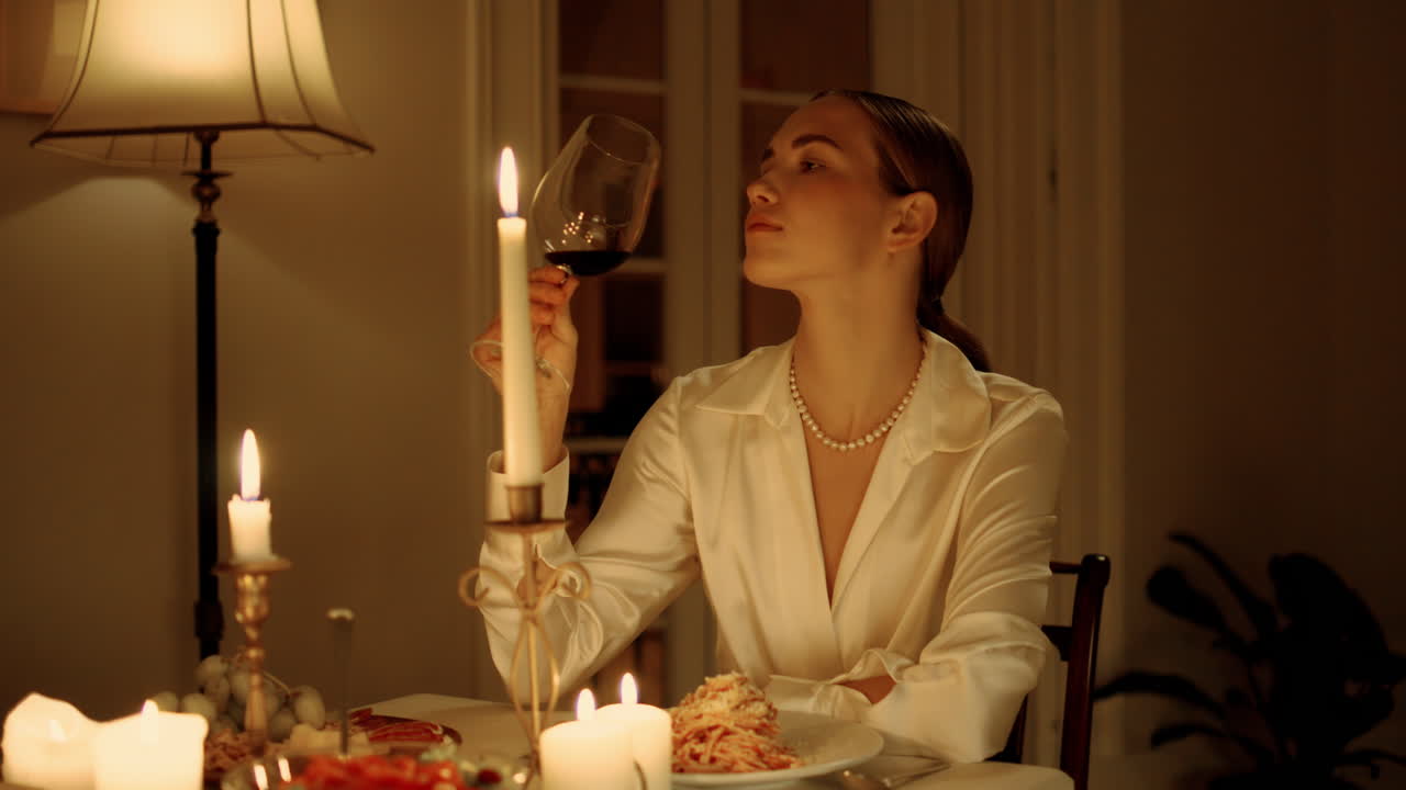 Primo piano di una signora elegante che assaggia un bicchiere di vino durante una cena romantica. Donna che beve alcol.