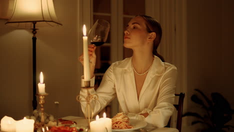 dama elegante degustando un vaso de vino cena romántica de cerca. mujer bebiendo alcohol