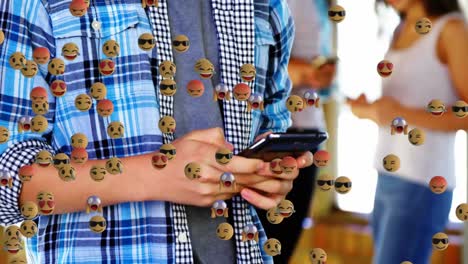 multiple face emojis floating against mid section of boy using smartphone