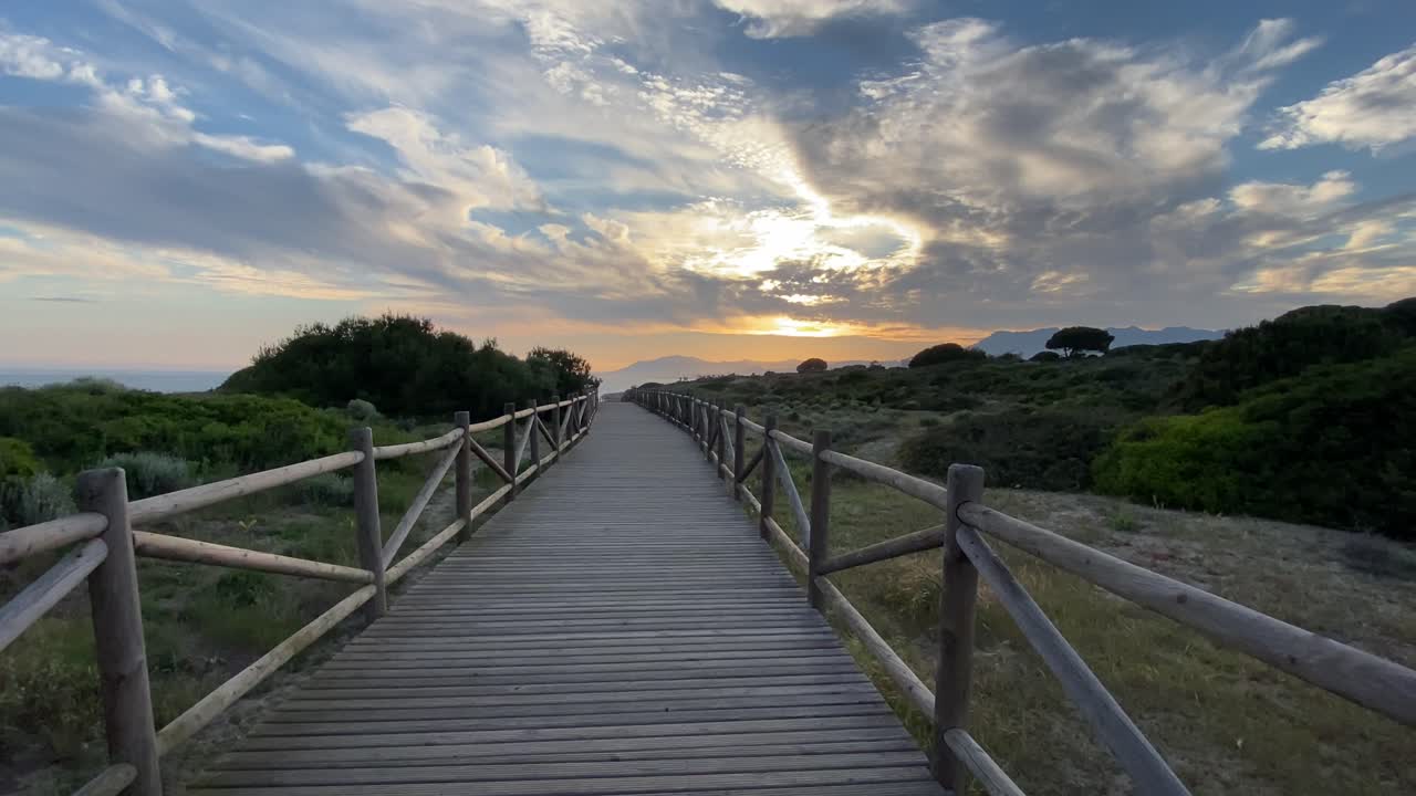 Walking on a wooden path on a southern Spanish beach in Marbella, with stormy skies.