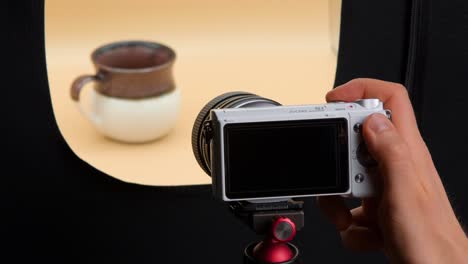 man taking pictures of coffee cup in a light box