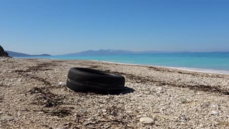 tire and plastics on beach, pollution of seaside on mediterranean coastline, environment disaster of garbage thrown on shoreline