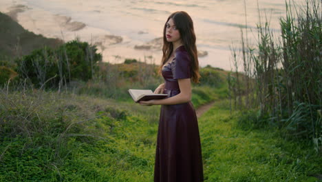 romantic woman looking book turning pages in beautiful ocean overcast day.