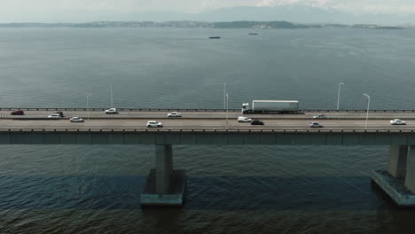 vista aérea de arriba hacia abajo automóviles y camiones conducen por el puente de hormigón que cruza el mar de rio-niteroi