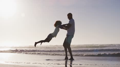 padre afroamericano y su hija jugando en la playa