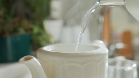 close up of steam rising from white ceramic mug as hot water is poured into it from kettle spout, capturing warm moment of tea preparation in cozy kitchen filled with soft light