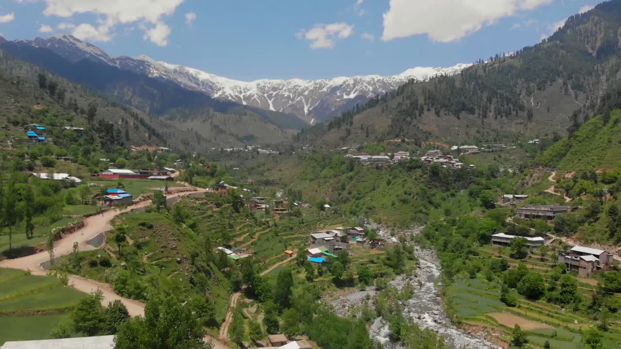 Vista aérea sobre una carretera a través del valle de Swat con montañas nevadas a la distancia