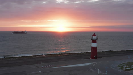 the lighthouse of westkapelle during a bright orange sunset, with a lot of wind