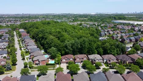 drone flying up over a forest in the middle of a mississauga neighborhood on a summer day