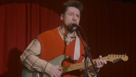 male musician playing guitar and singing during live music perfomance 2