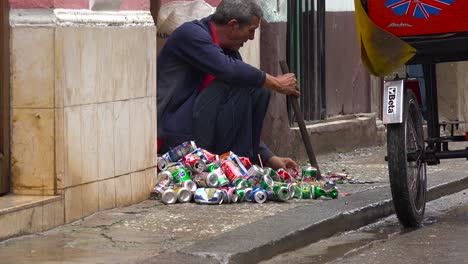 Un-Hombre-En-La-Calle-Aplasta-Y-Recicla-Latas-De-Aluminio-En-La-Habana-Cuba