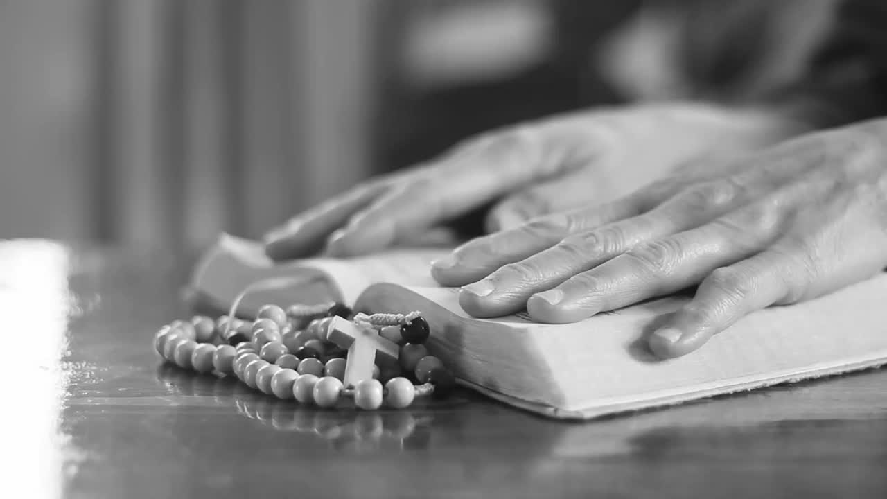 Hands Praying with Rosary and Bible