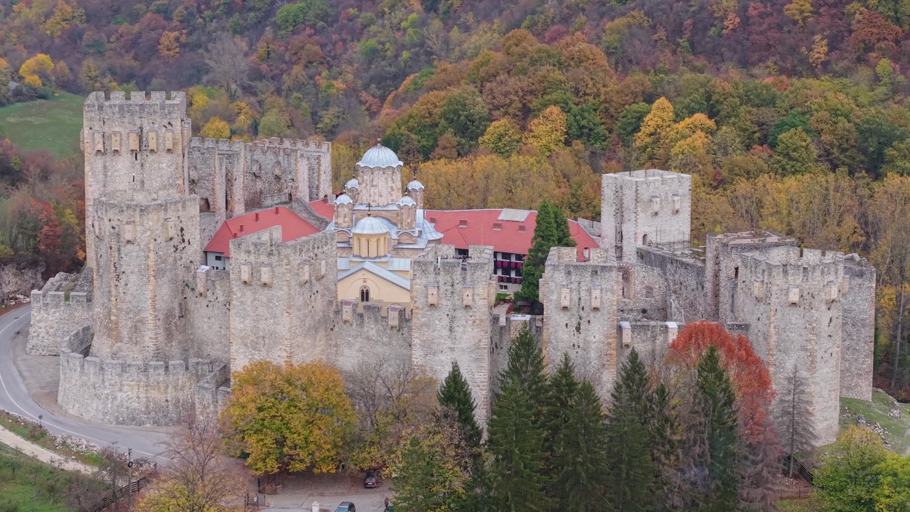 A scenic view of Manasija Monastery surrounded by colorful winter trees, blending medieval Serbian architecture with a vibrant seasonal landscape and peaceful natural atmosphere.