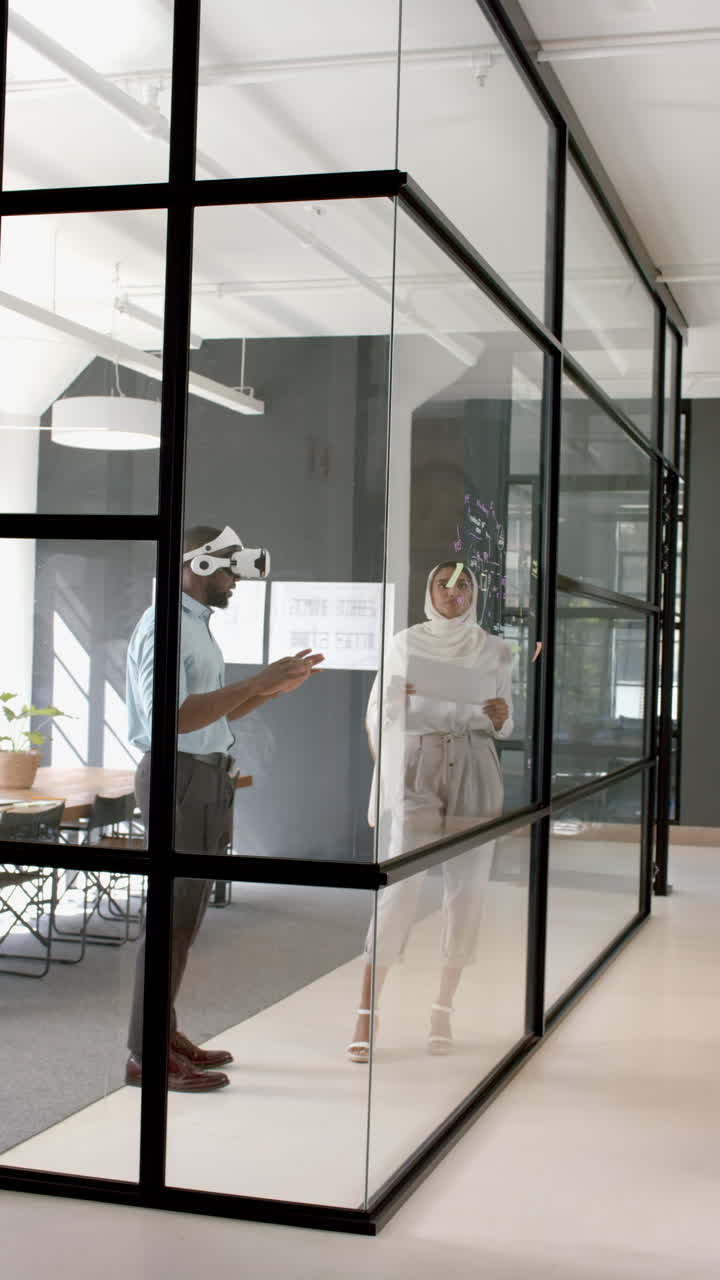 Vertical video: Using VR headset, businessman interacting with female colleague in modern office