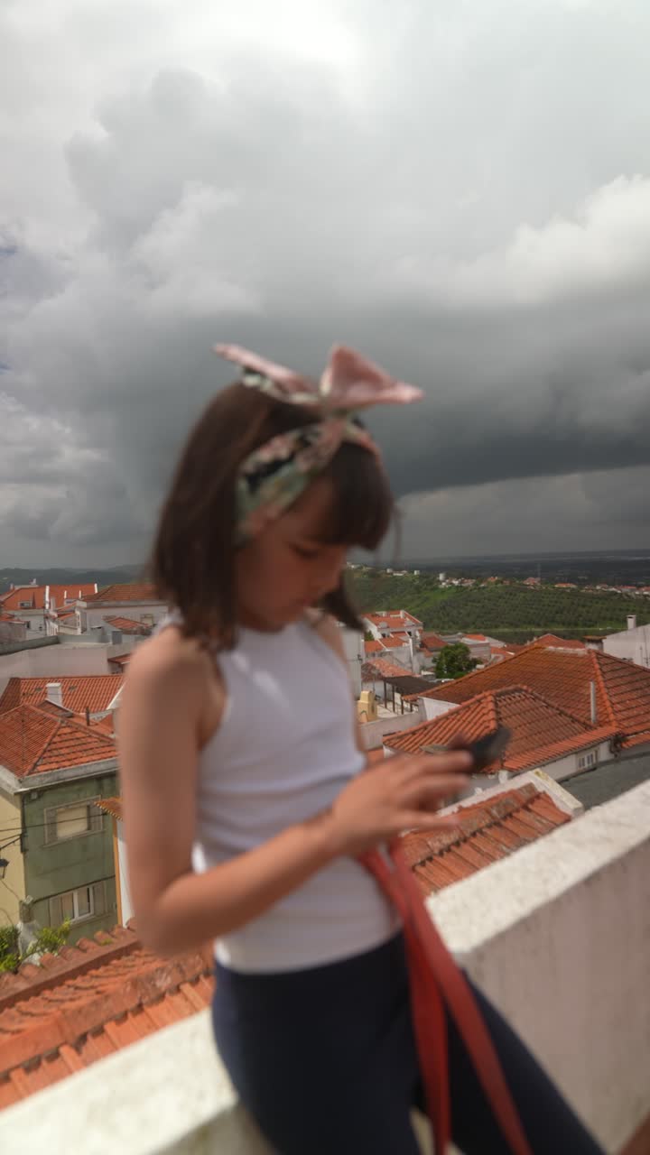 Girl on a rooftop with a smartphone on a cloudy day