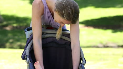 mother tending to her baby girl in her pram in the park