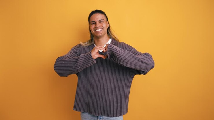 Giovane uomo felice che manda un bacio e fa il gesto del cuore.