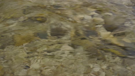 textura de flujo de agua con guijarros de lecho de río bajo un río cristalino frío, patrón líquido