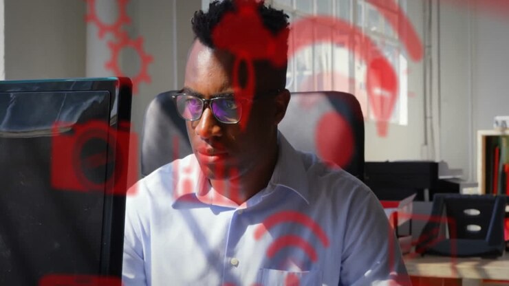 Animation of media icons over biracial businessman using computer in office