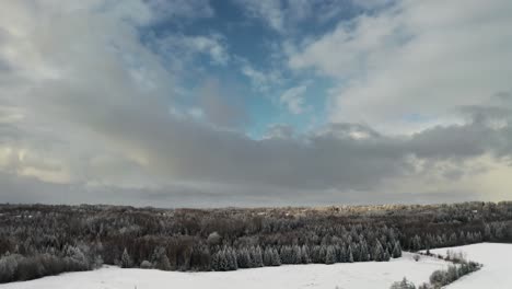 flying over countryside landscape in snow covered winter season. aerial drone view of beautiful sky over the forest. frozen forest trees in bright winter day. clean environment.