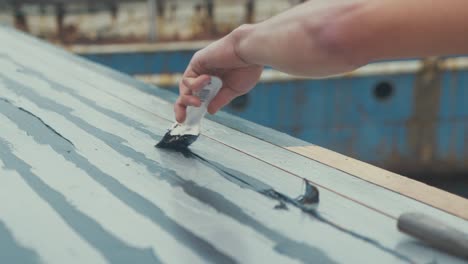 Flattening-sika-flex-mastic-sealant-into-gaps-between-roof-planking-of-old-wooden-boat-roof-cabin