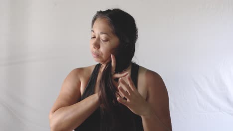 una mujer latina adulta se peina el cabello largo y negro con un peine después de bañarse.