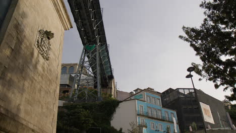 a perspective beneath the dom luis i bridge, with old buildings lining the waterfront, in porto, portugal - low angle shot