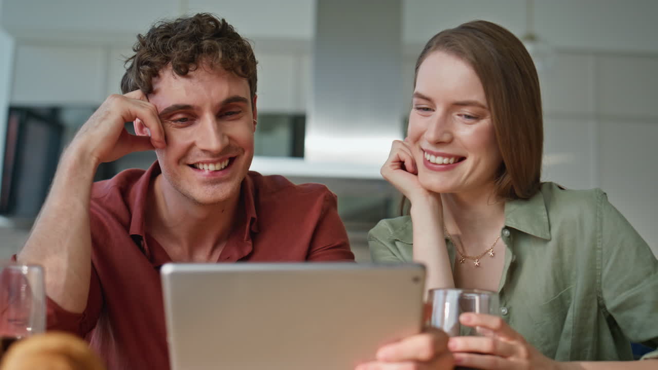 Laughing couple looking tablet relaxing together at home closeup. Joyful spouses