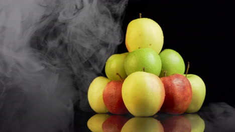 el humo cubre la pila de manzanas maduras y jugosas con gotas de agua en ellas.