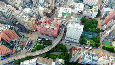 Traffic-passing-through-a-Car-park-building-in-downtown-Hong-Kong,-with-city-mega-buildings,-Aerial-view