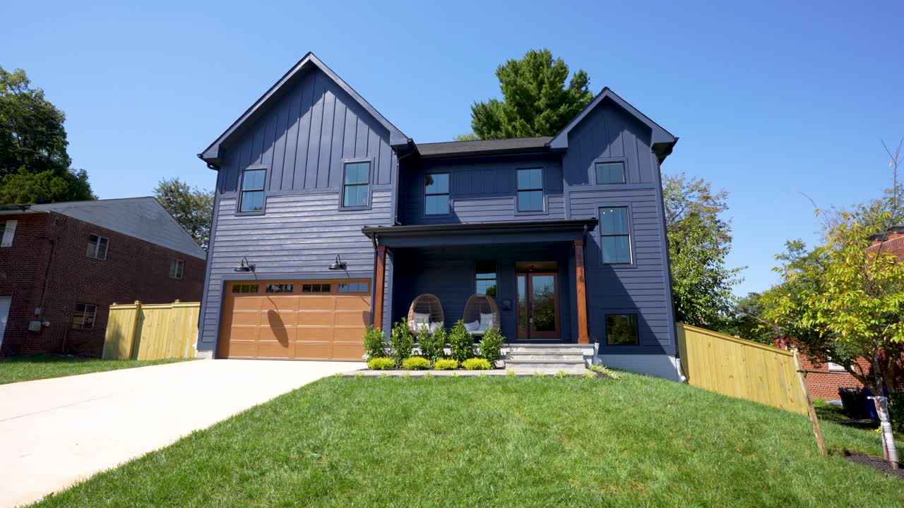 The camera pans smoothly right to left, revealing a stunning dark blue house under a bright sunny sky, surrounded by vibrant green grass and a cheerful, inviting atmosphere.