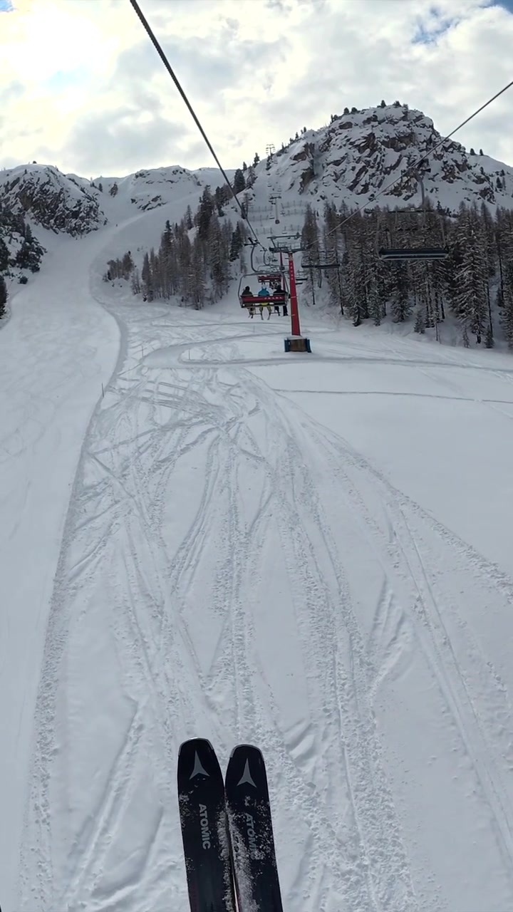 Skiers Riding Chairlift Over Snowy Mountain Slope