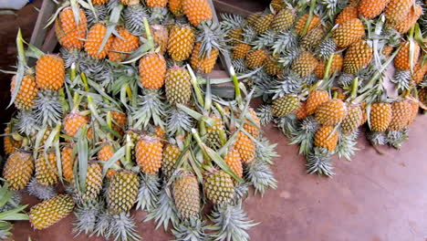 bright ripe pineapples neatly stacked on wooden racks in a tropical open-air fruit stall