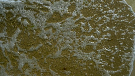 View-of-the-sea-shore,-Foam-from-water-poured-into-the-sand,-sand-and-water-on-the-coast