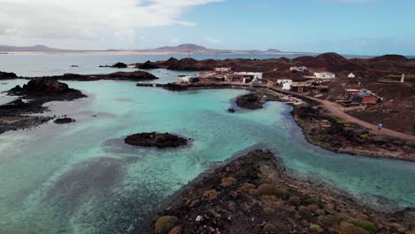 turquoise waters, rocky coastlines, and volcanic terrain with distant mountains, showcasing coastal beauty and serene landscapes. 4k aerial circle drone view of puertito isla de lobos, fuerteventura