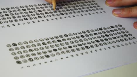 male student hand testing doing examination test with standardized test form and answers bubbled