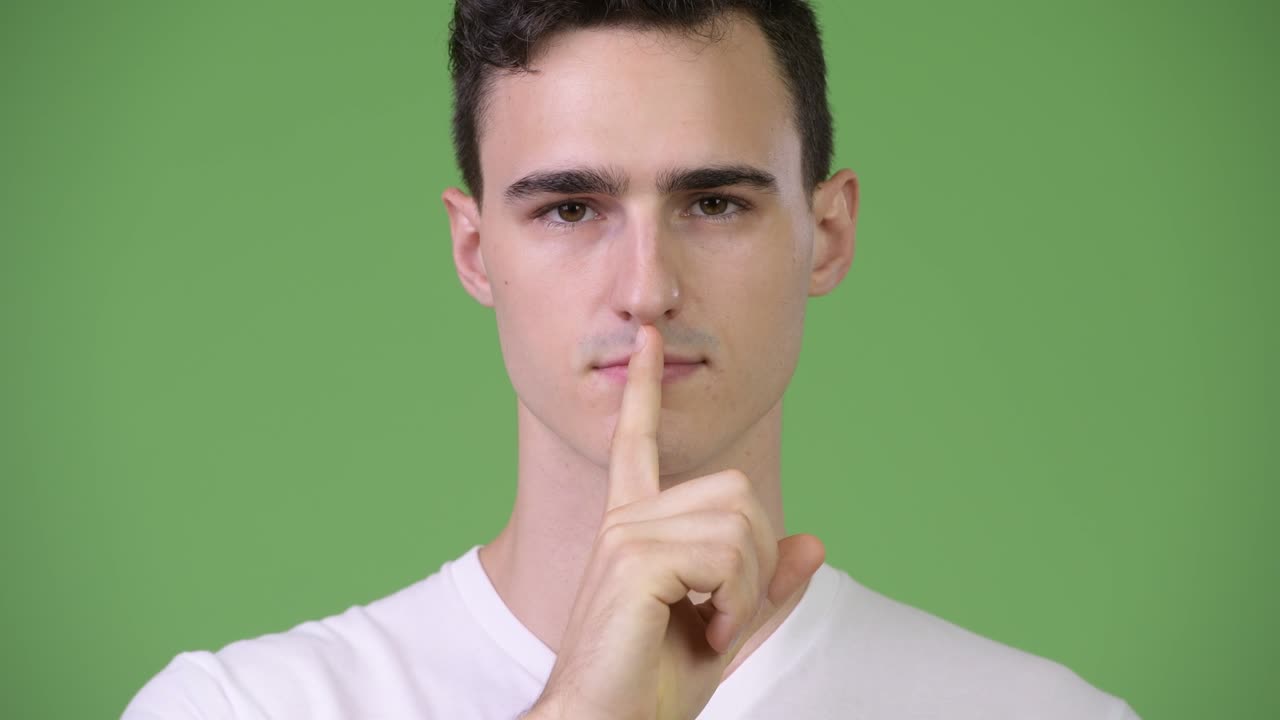 Young handsome man with finger on lips