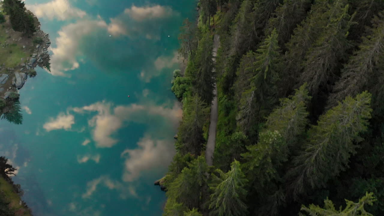 reflejos del cielo en el lago azul claro al borde de un bosque en caumasee suiza - toma aérea