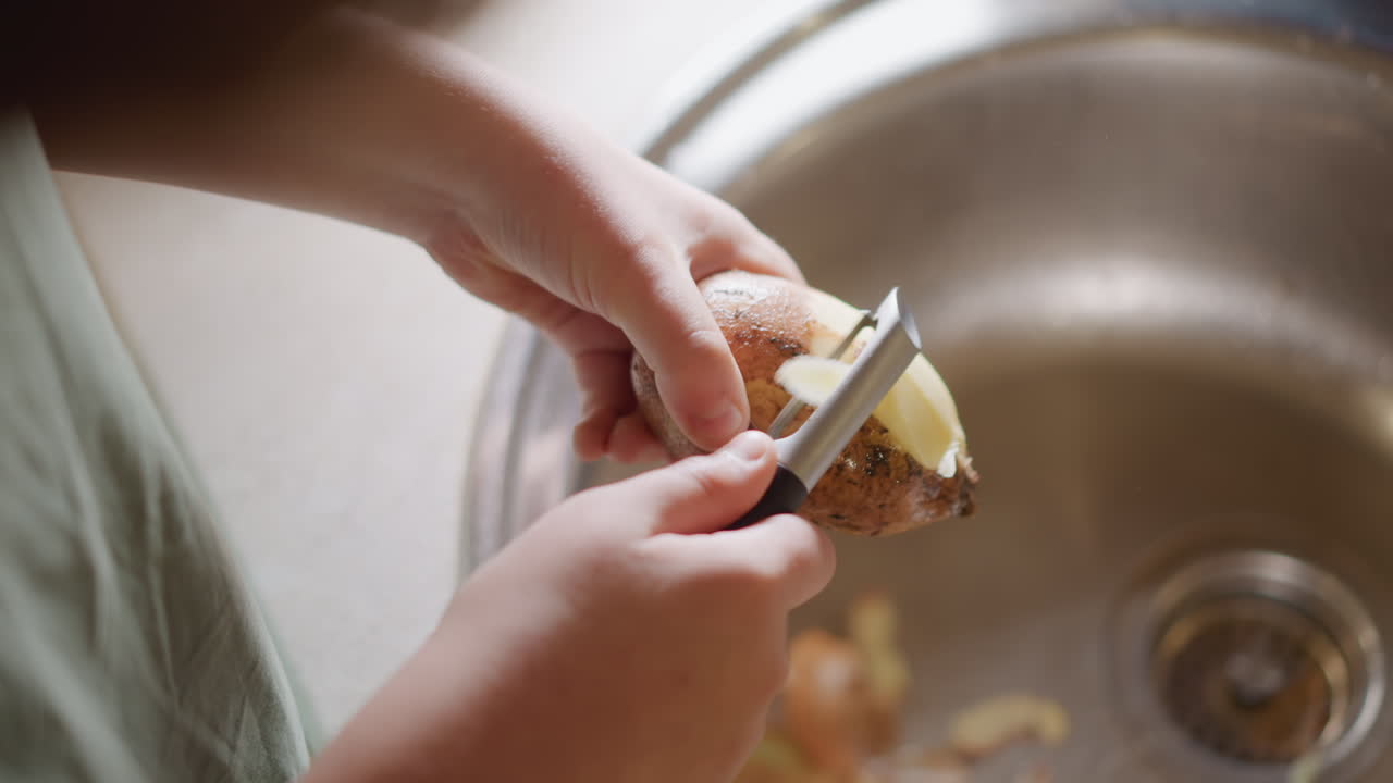 Calm morning kitchen activity. Tranquil morning environment with gentle potato peeling process. Serene home setting showcasing someone carefully peeling potatoes during peaceful sunrise hours