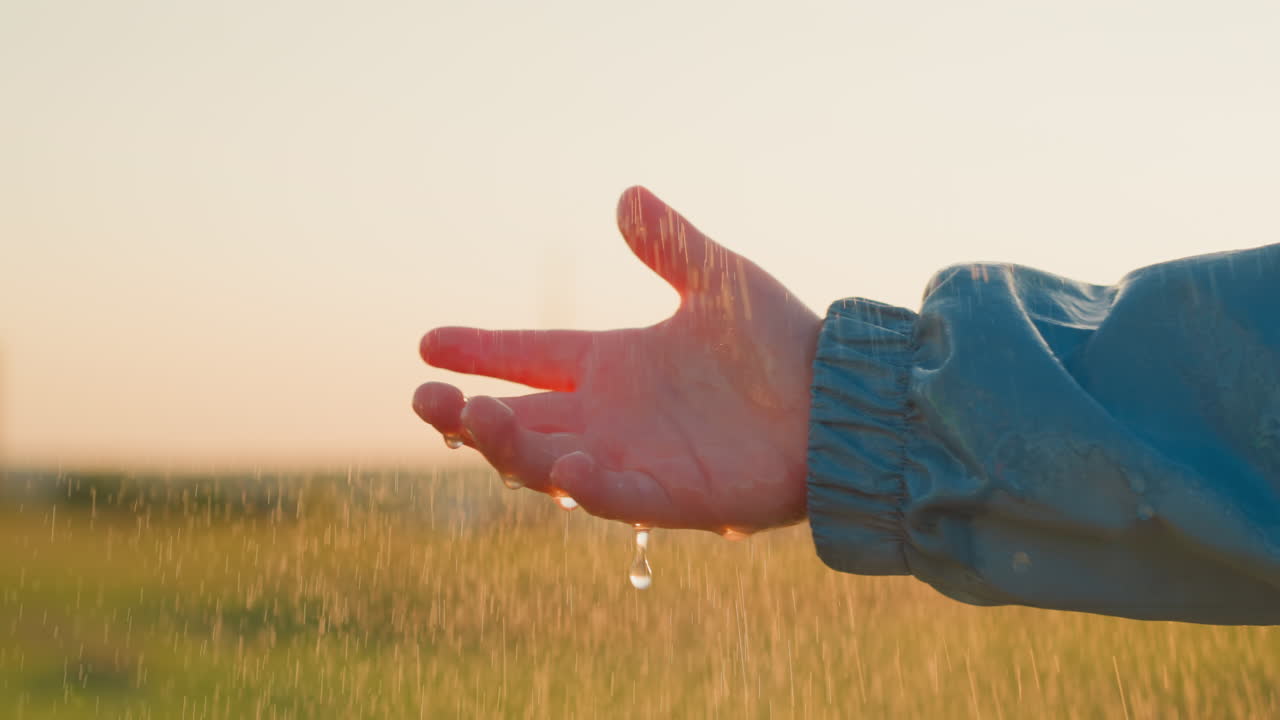 소년은 손바닥을 들고 비를 환영합니다. 아이는 지구와 연결되는 느낌을 느니다.