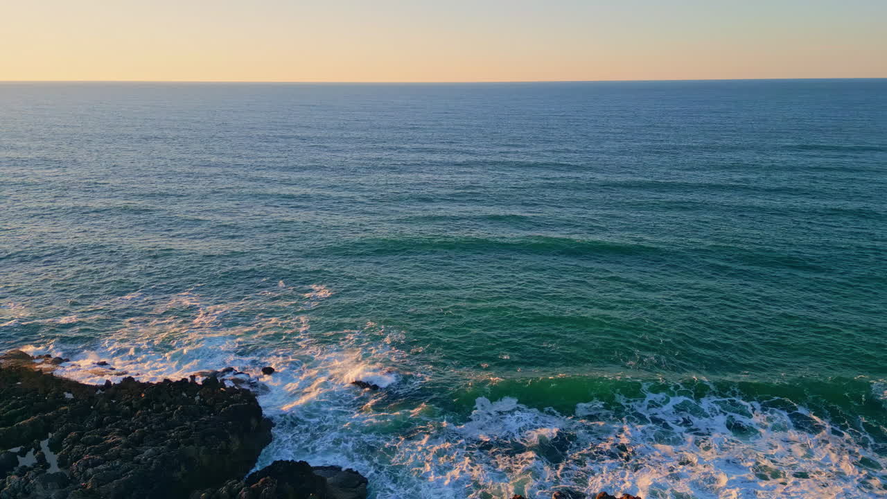 Foamy waves rolling rocky coastline aerial picturesque ocean view in slow motion